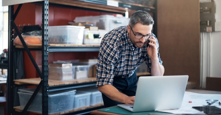 A man working on a laptop amid supplies, suggesting small-business ownership